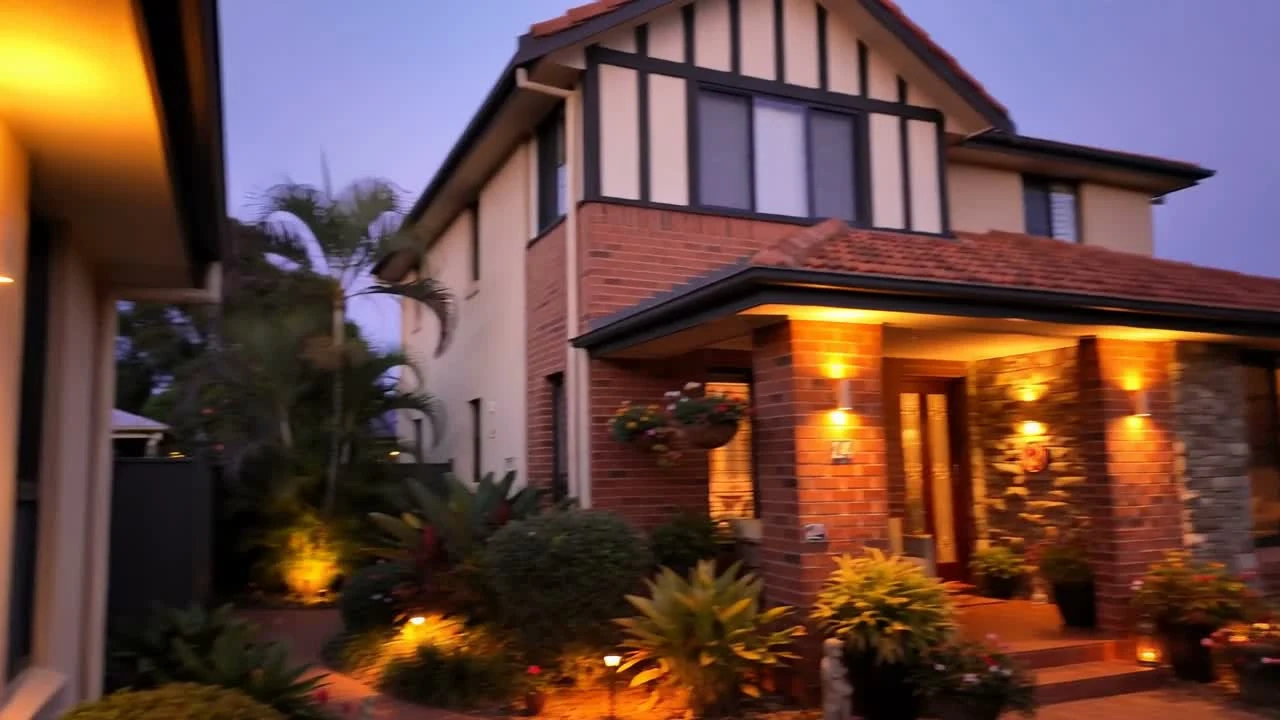 Exterior de una villa australiana con iluminación arquitectónica cálida al atardecer