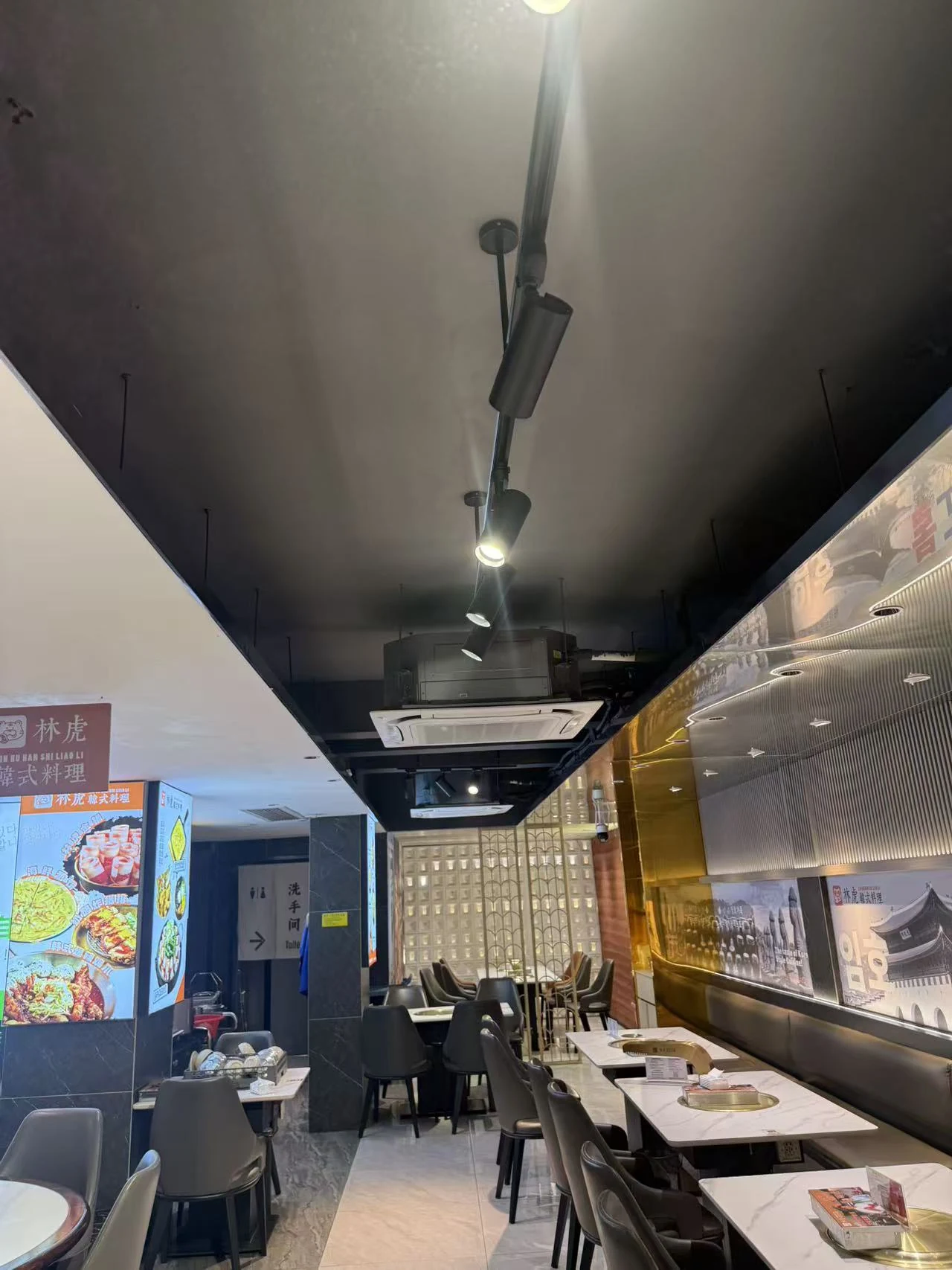Iluminación sobre carril, aire acondicionado de techo y mesas en Lin Hu Korean BBQ, Guangzhou.