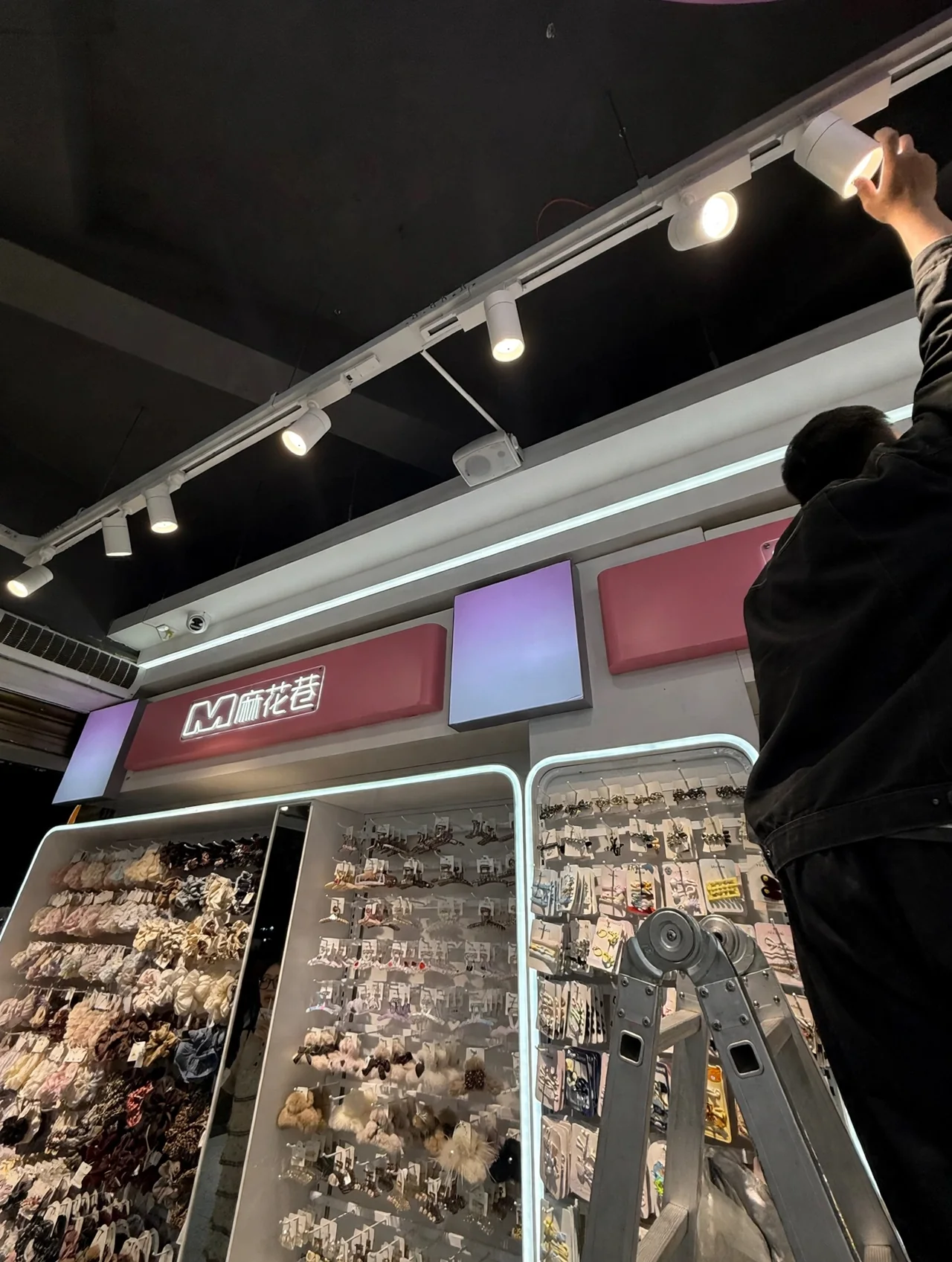 Vor-Ort-Ausrichtung eines LED-Stromschienenstrahlers über der Accessoire-Präsentation im Mahua Lane Geschäft in Changsha.